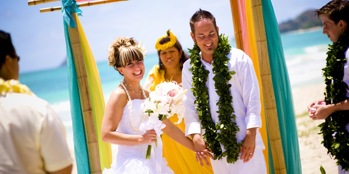 beach wedding cermeony with tiki men and hawaiian flower theme 